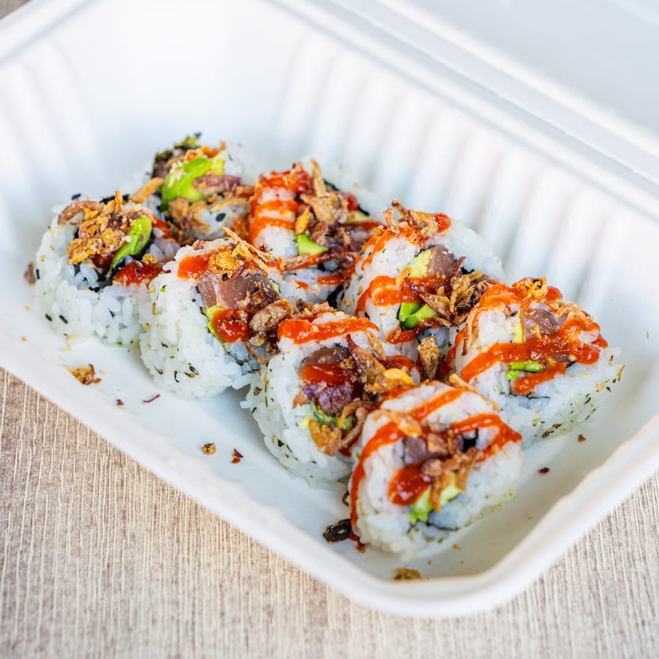 Ramen Kenjo's sushi rolls with avocado, tuna, crispy onions, and spicy sauce in a takeout container.