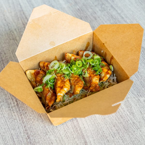 Ramen Kenjo's Japanese gyoza dumplings with sauce and green onions in a takeout box.