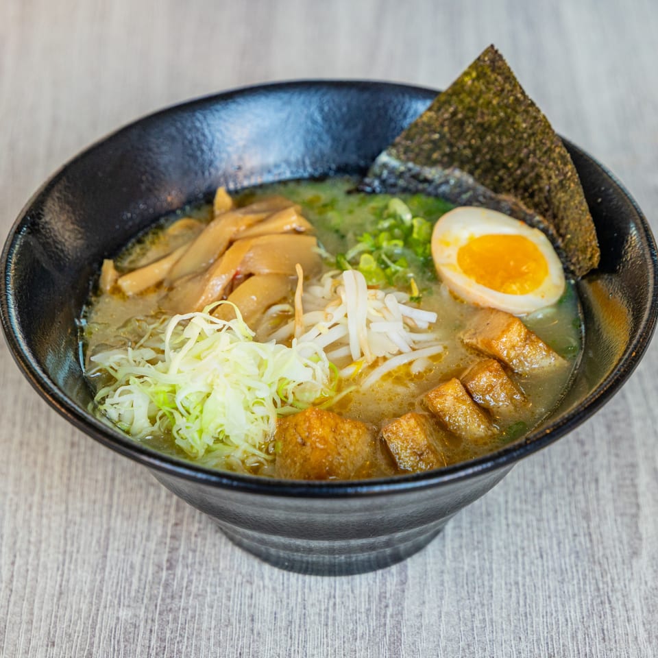 A bowl of Ramen Kenjo's ramen with broth, noodles, egg, seaweed, bamboo shoots, and tofu.